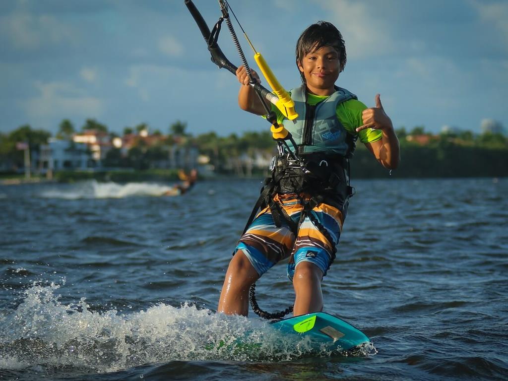 Uśmiechnięte dziecko pozujące podczas zabawy kitesurfingowej.